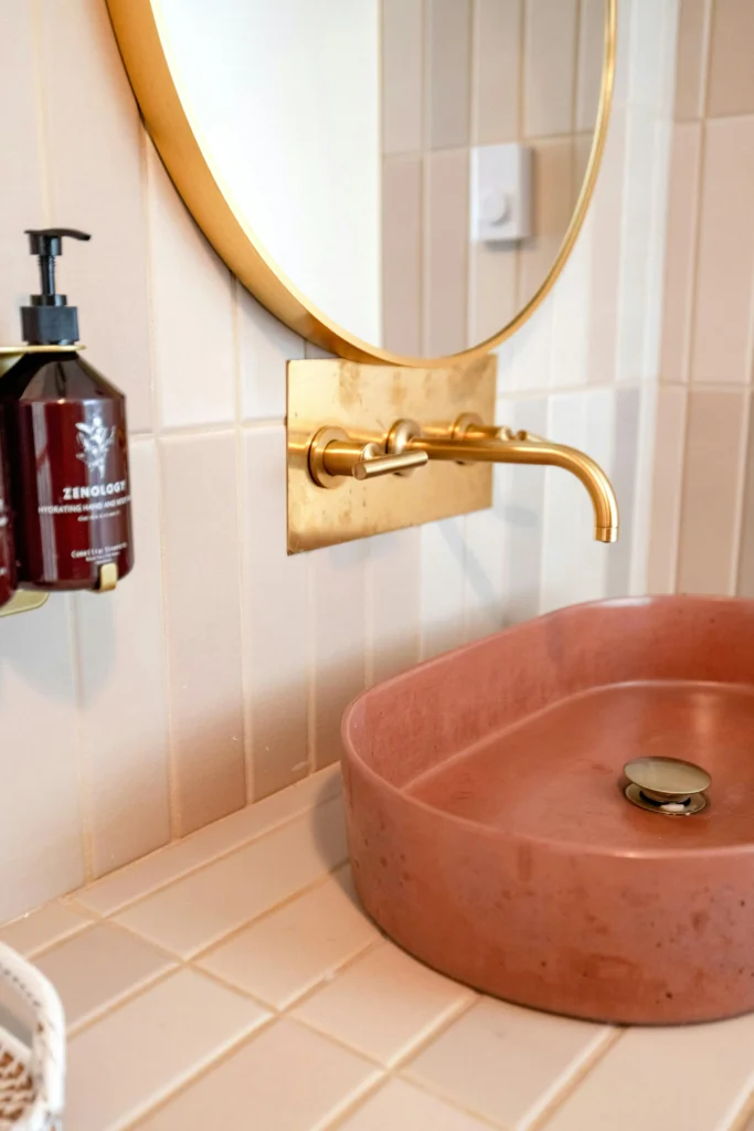 Baño con Lavabo Rosa y Grifería Dorada