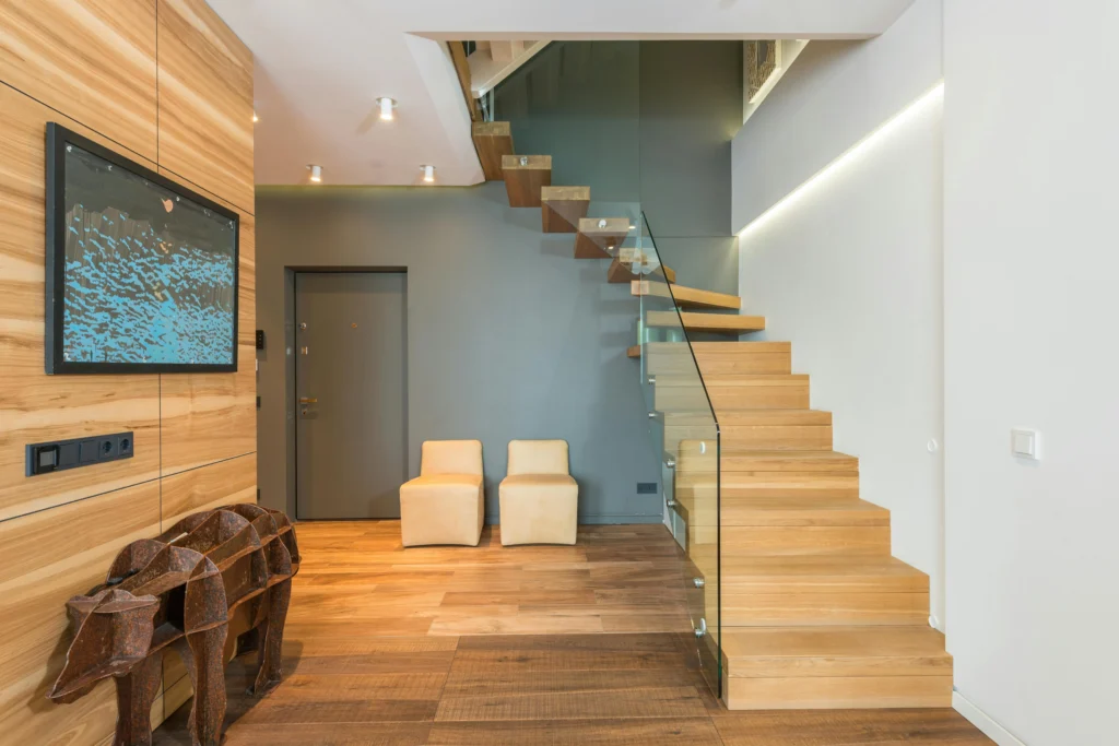 inicio Escalera de Madera Clara con Baranda de Vidrio y Pared Gris