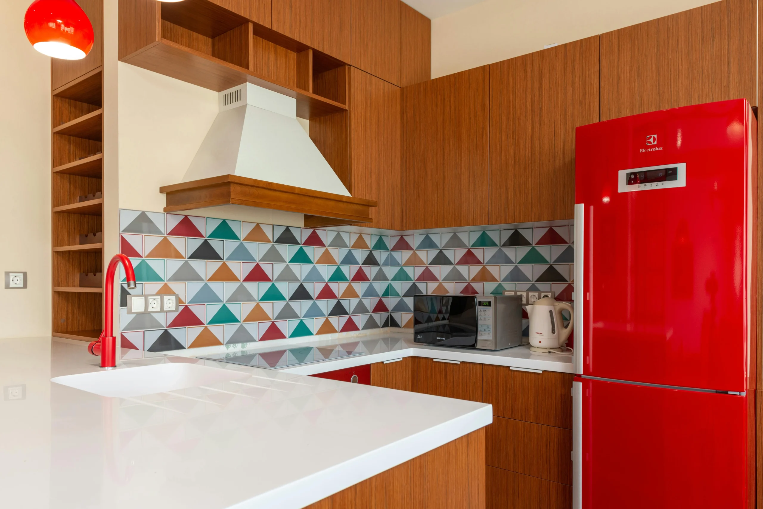 Cocina en L con Geometría Colorida y Electrodomésticos Rojos