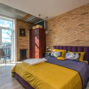 Dormitorio Industrial con Ladrillo Visto y Textiles en Mostaza y Violeta