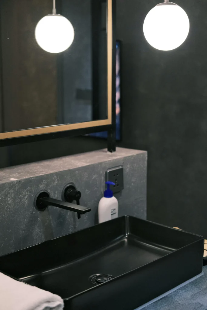 Lavabo negro sobre encimera de piedra gris con grifería negra