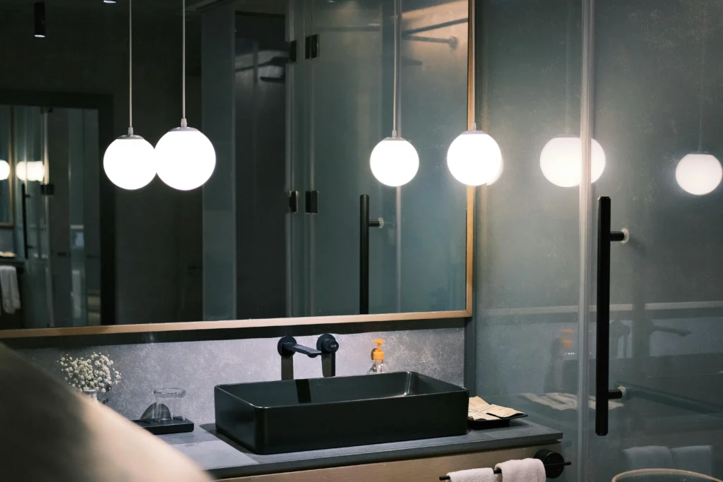 Baño moderno con lavabo negro y espejo retroiluminado