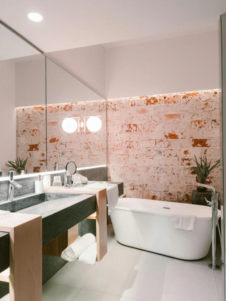 Baño Minimalista con Pared de Ladrillo Envejecido y Bañera Exenta