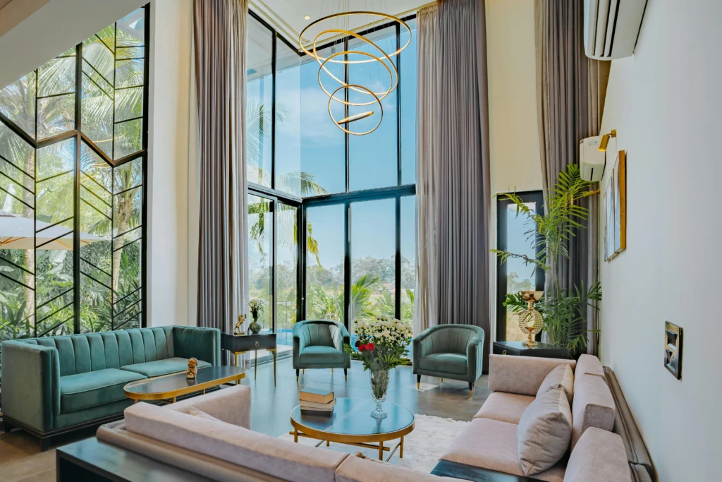 inicio Salón de Doble Altura con Sofás Verdes y Lámpara Escultural Dorada