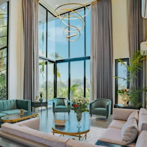 Salón de Doble Altura con Sofás Verdes y Lámpara Escultural Dorada