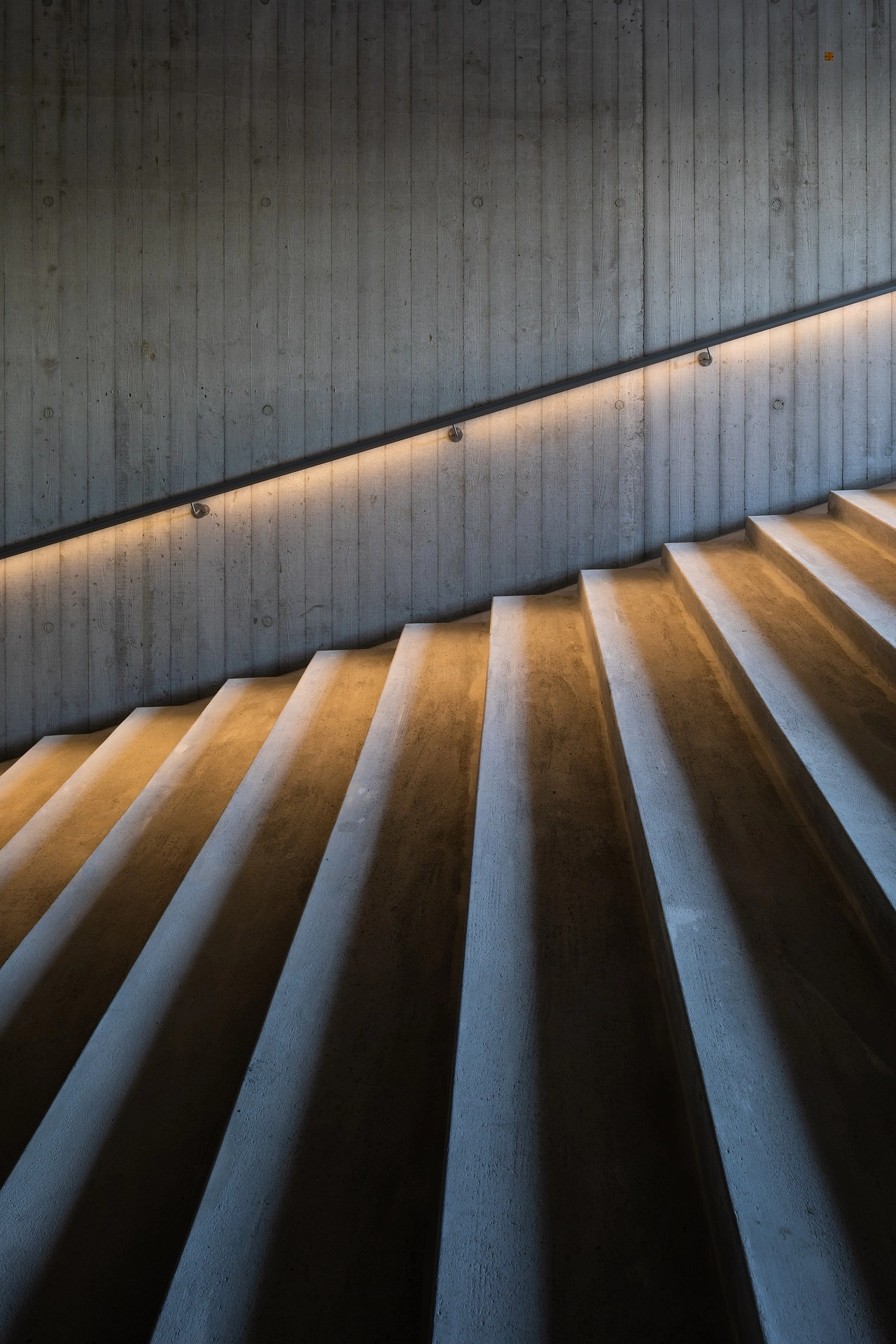 Escalera de concreto con iluminación indirecta en pasamanos