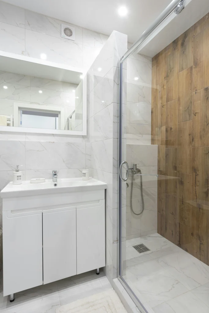 Baño Luminoso en Mármol Blanco con Ducha de Acento en Madera Cerámica